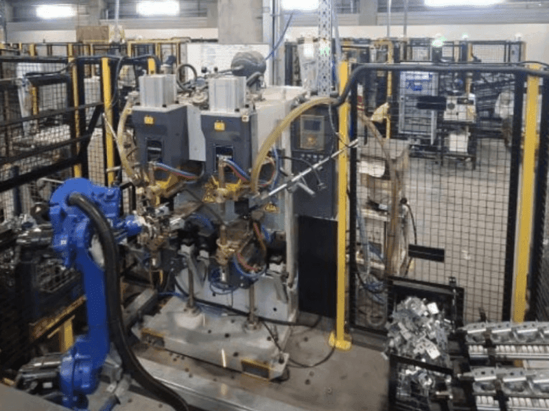 Real factory photo — full PRP automation cell, robots visible